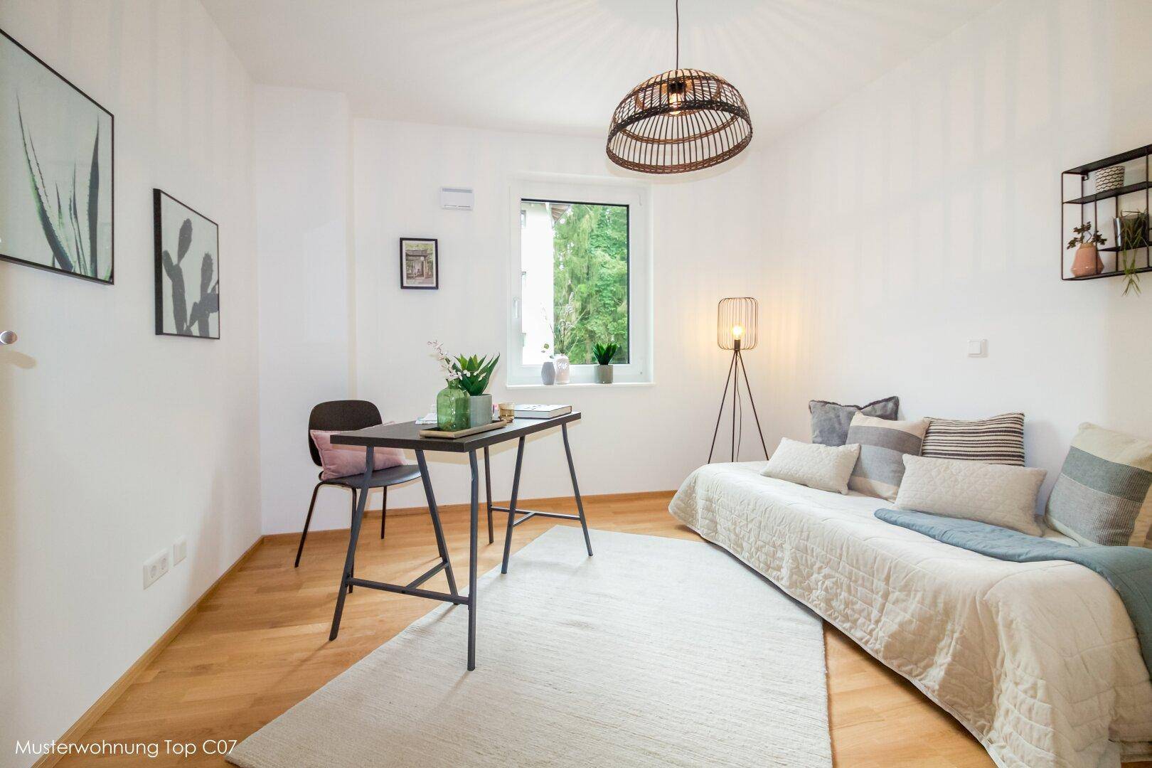 Helles Arbeitszimmer mit Holzfußboden, großem Fenster und einer gemütlichen Tagesliege.
