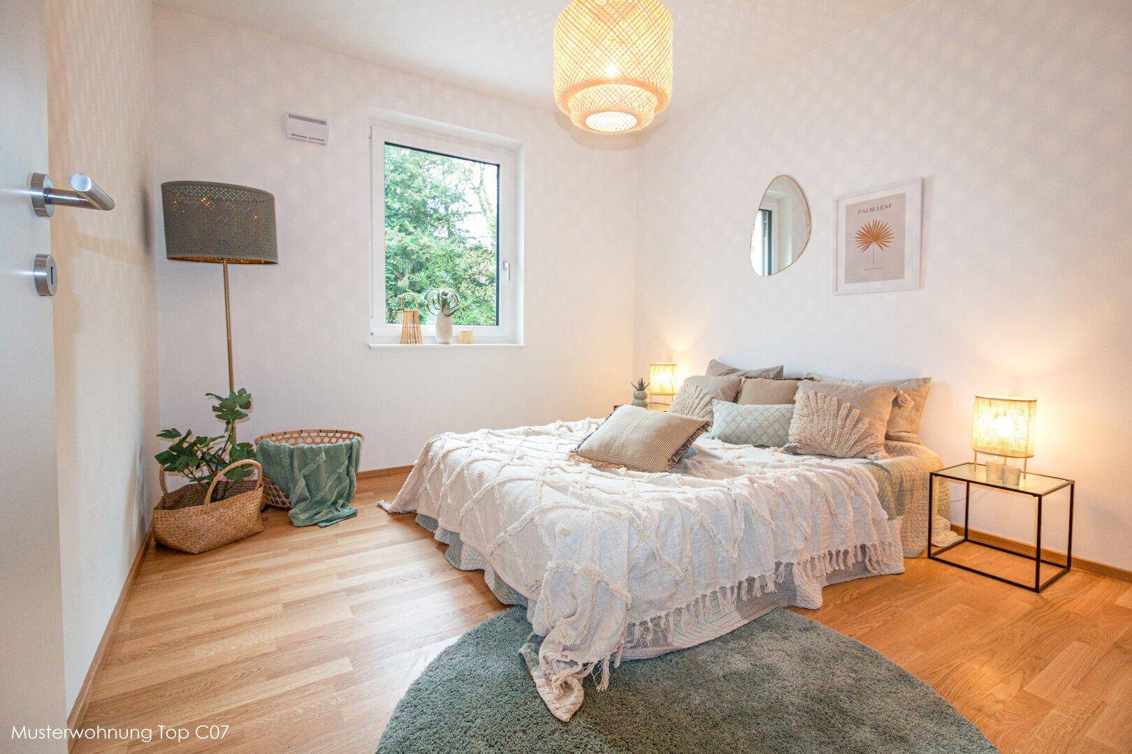 Gemütliches Schlafzimmer mit Doppelbett, Holzfußboden und einem großen Fenster mit Grünblick.