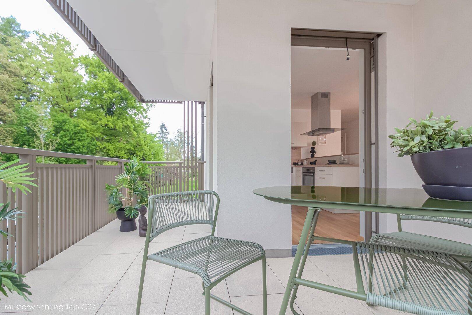 Geräumiger Balkon mit Fliesenboden, Sitzgelegenheiten und Blick ins Grüne.
