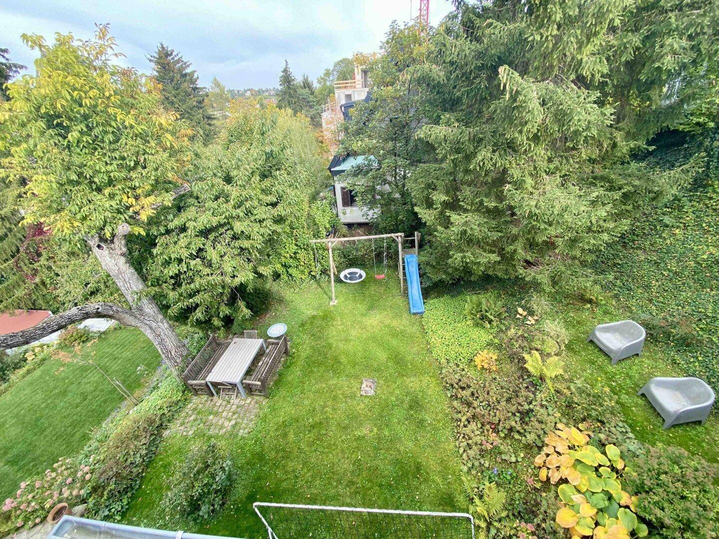 Großer Garten mit Rasenfläche, Schaukel und Rutsche, ideal für Familien.