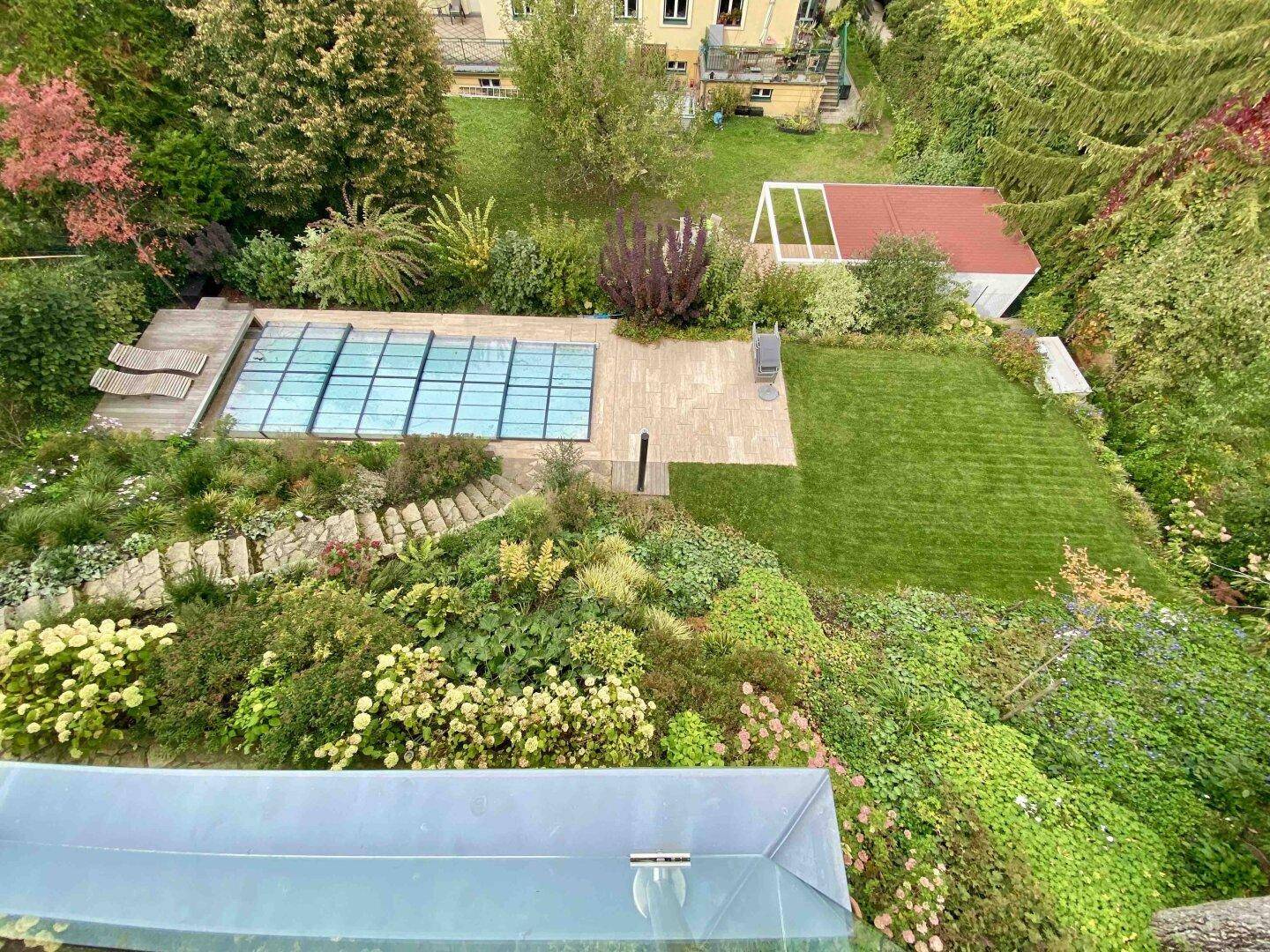 Weitläufiger Garten mit Pool, Liegeflächen und vielfältiger Bepflanzung.