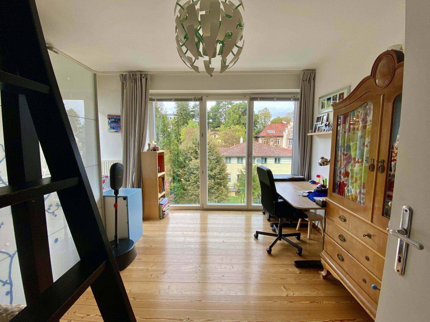 Kinderzimmer oder Arbeitszimmer mit Holzboden und großen Fenstern zum Garten.