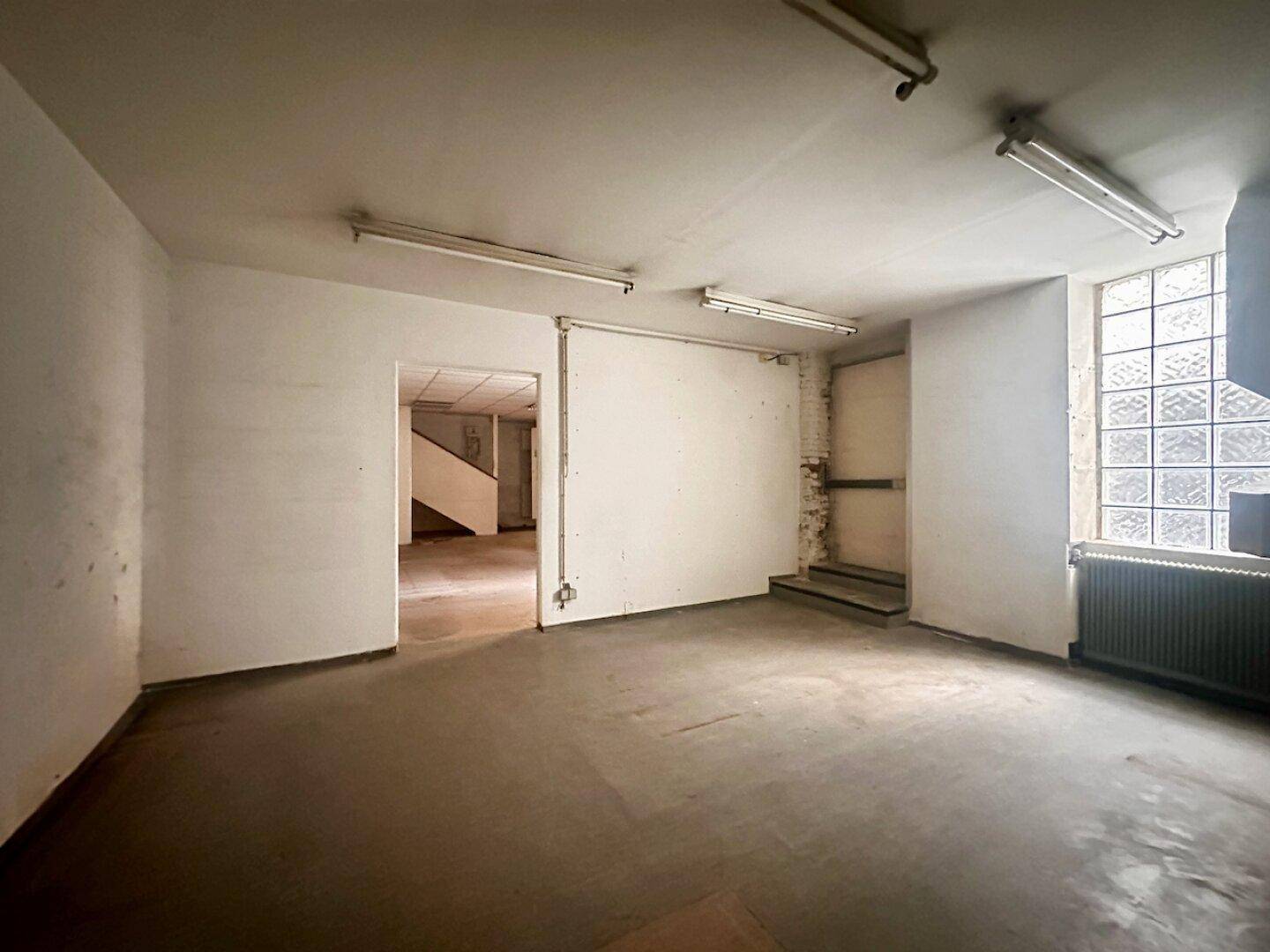 Gewerberaum mit Glasbausteinfenster und Blick auf eine interne Treppe, die verschiedene Ebenen verbindet.