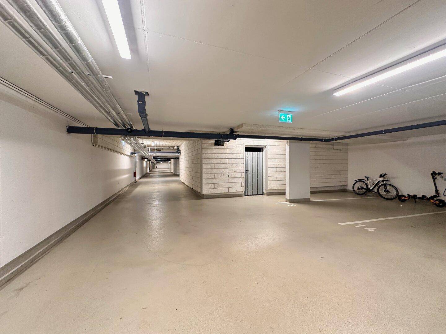 Geräumige Tiefgarage mit mehreren Stellplätzen und guter Beleuchtung, inklusive Fahrradabstellbereich.