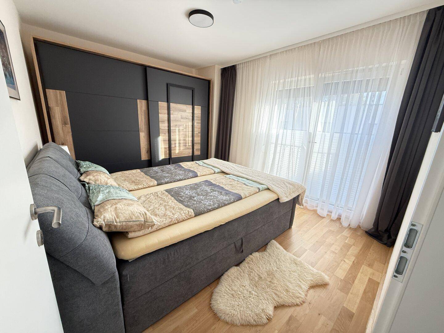 Gemütliches Schlafzimmer mit Doppelbett, großem Schiebetürenschrank und Zugang zum Balkon.