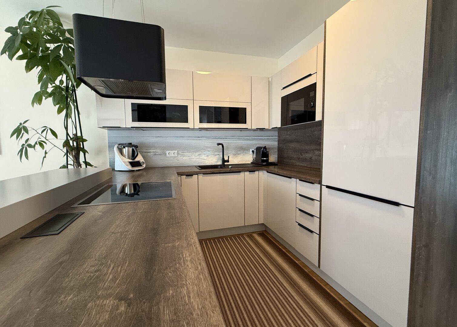 Moderne Einbauküche mit hellen Hochglanzfronten, Holz-Arbeitsplatten und Induktionskochfeld.