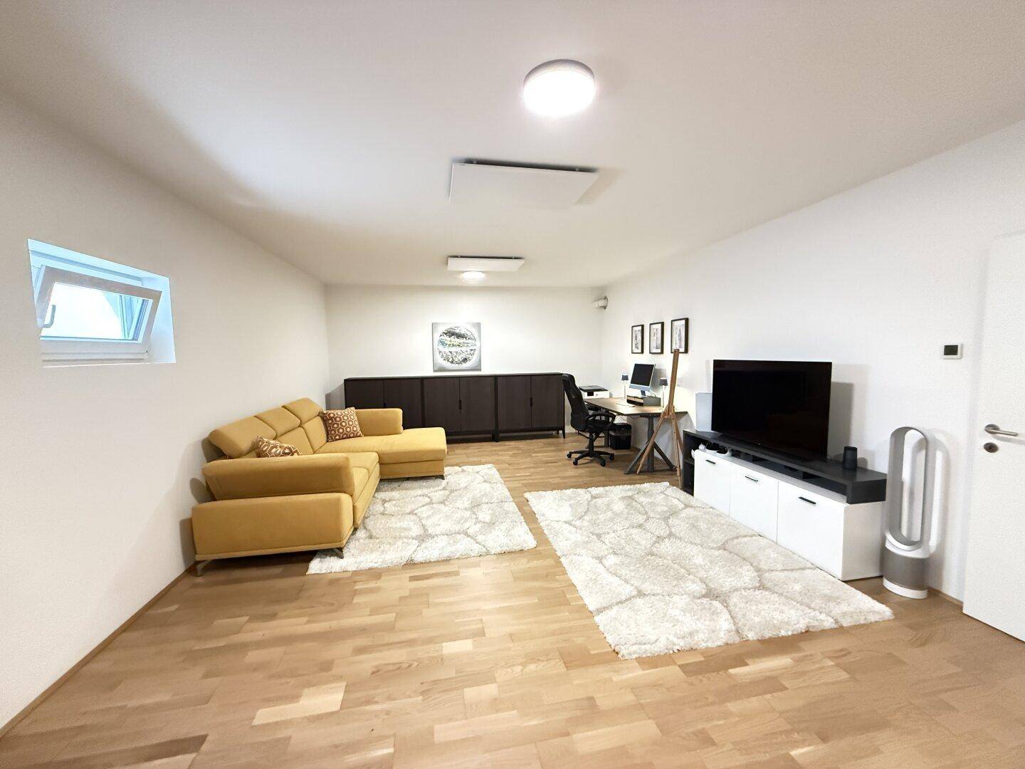 Ausgebauter Kellerraum als vielseitiger Hobby- oder Medienraum mit Sofa und Schreibtisch.