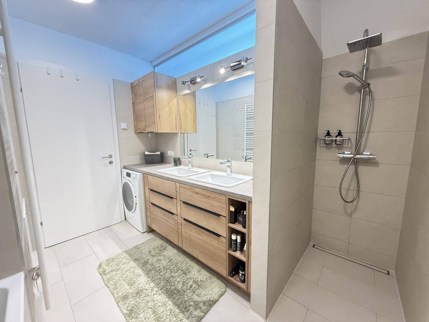Elegantes Badezimmer mit begehbarer Dusche, Doppelwaschbecken und modernen Armaturen.