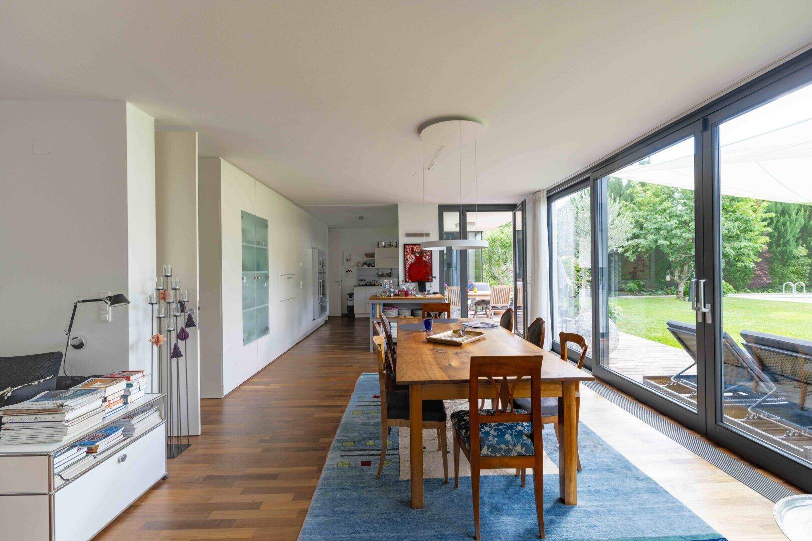 Offener Essbereich mit Holztisch, Parkettboden und Zugang zur Terrasse und zum Garten.