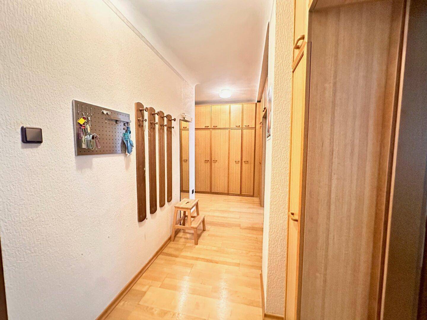 Langer Flur mit durchgehenden Holz-Einbauschränken und einem Garderobenbereich.