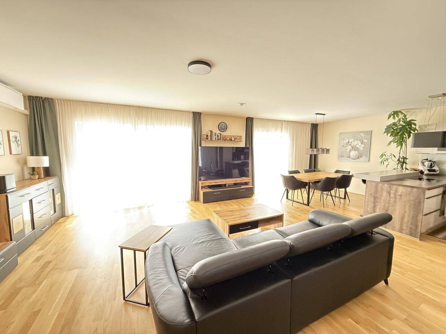 Offener Wohn- und Essbereich mit Holzboden, bequemer Couch und Zugang zur Terrasse.