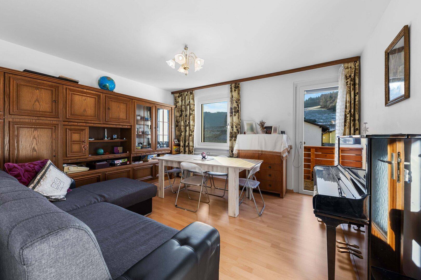 Geräumiger Wohn-Essbereich mit großem Schrank, Sofa, Esstisch und Klavier, hell und einladend.