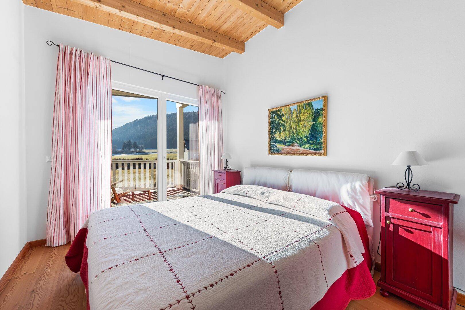Helles Schlafzimmer mit Holzbalkendecke und direktem Zugang zum Balkon.