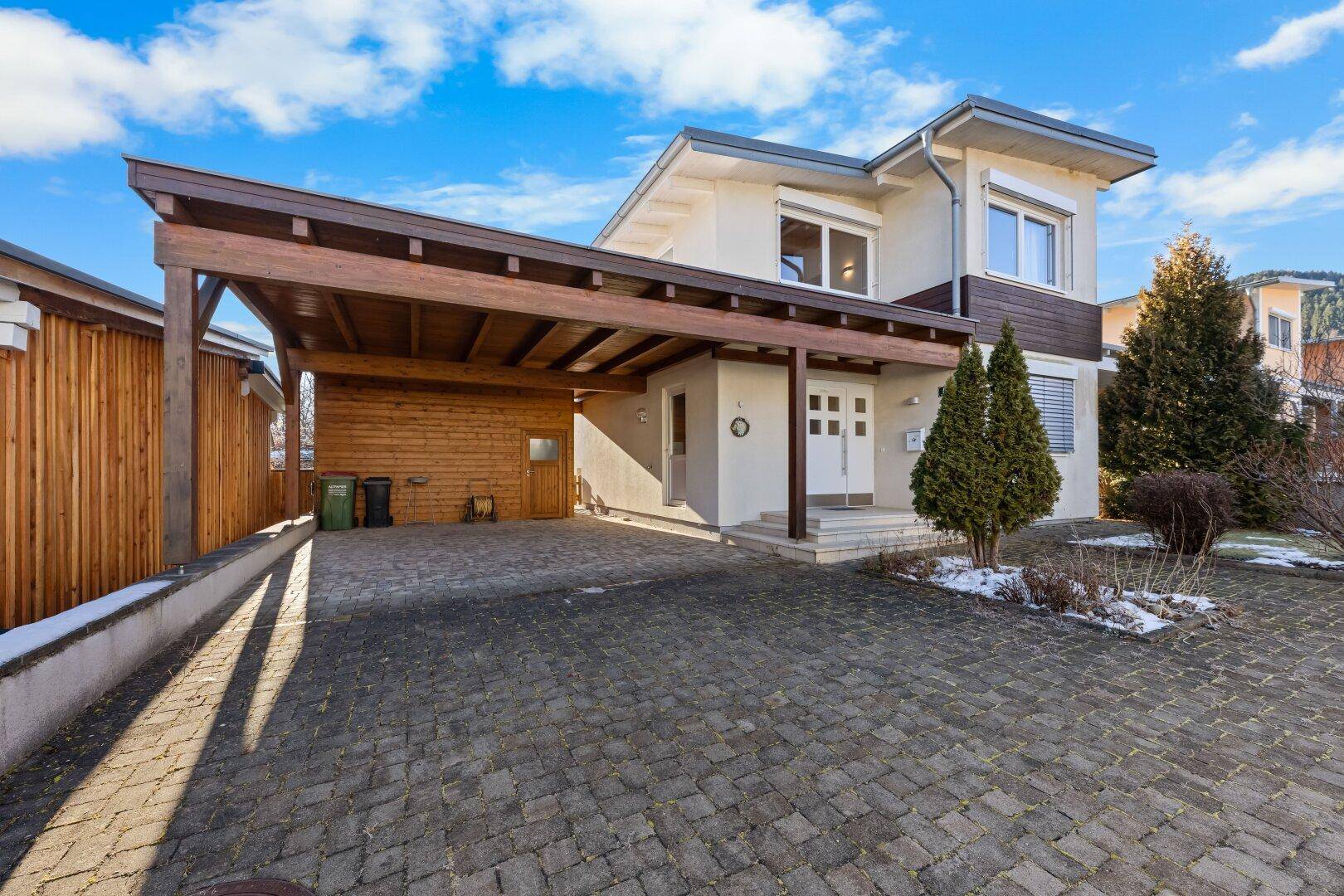 Vorderansicht des Hauses mit Carport, gepflasterter Einfahrt und Vorgarten.
