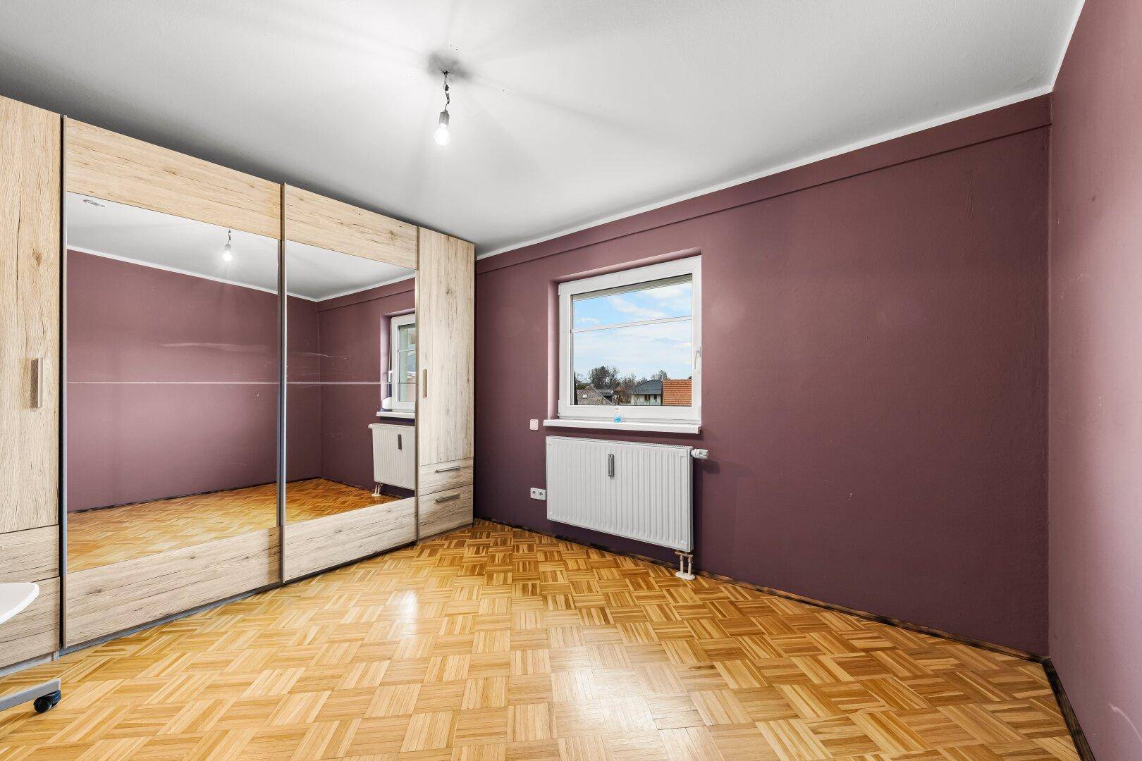Geräumiges Schlafzimmer mit Parkettboden und großem Spiegelschrank.