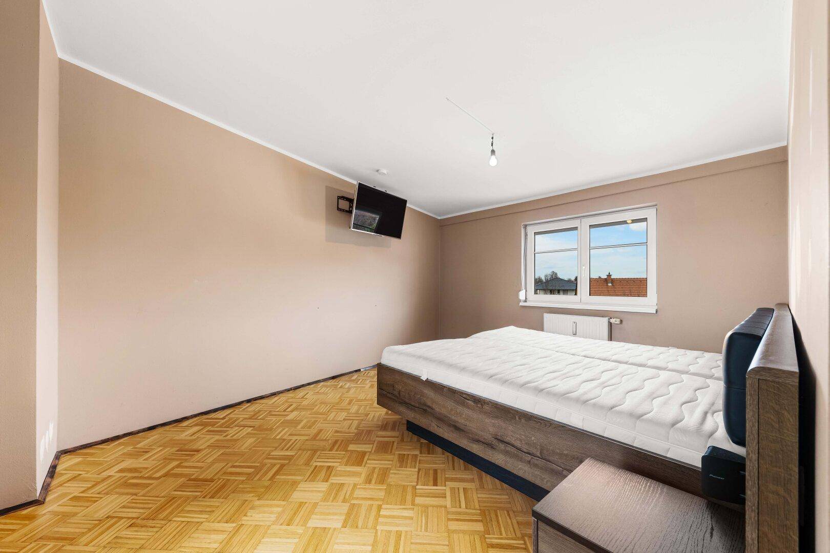 Schlafzimmer mit Parkettboden und einem Doppelbett, bereit zur individuellen Gestaltung.