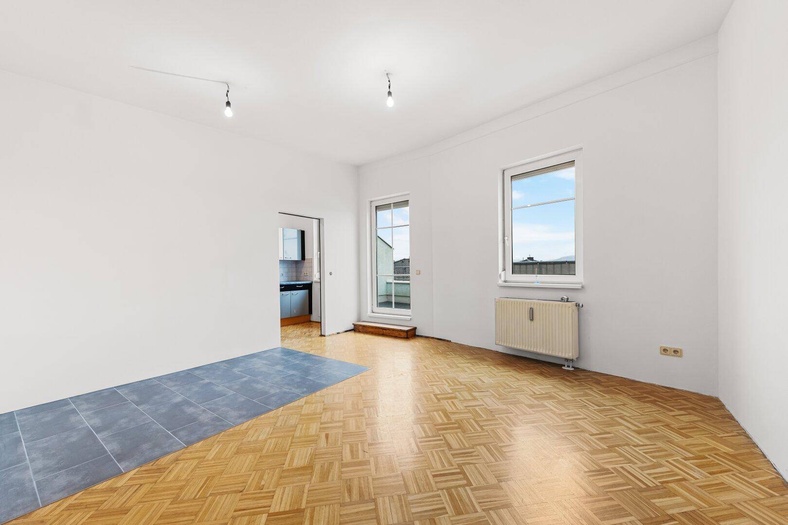 Helles Wohnzimmer mit Parkettboden und Zugang zur Terrasse.
