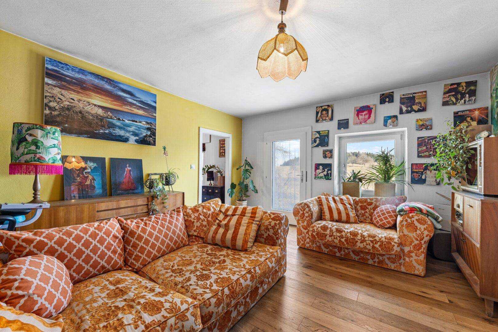 Lebhaftes Wohnzimmer mit gelben Wänden, floralen Sofas und einer Sammlung von Schallplatten an der Wand.