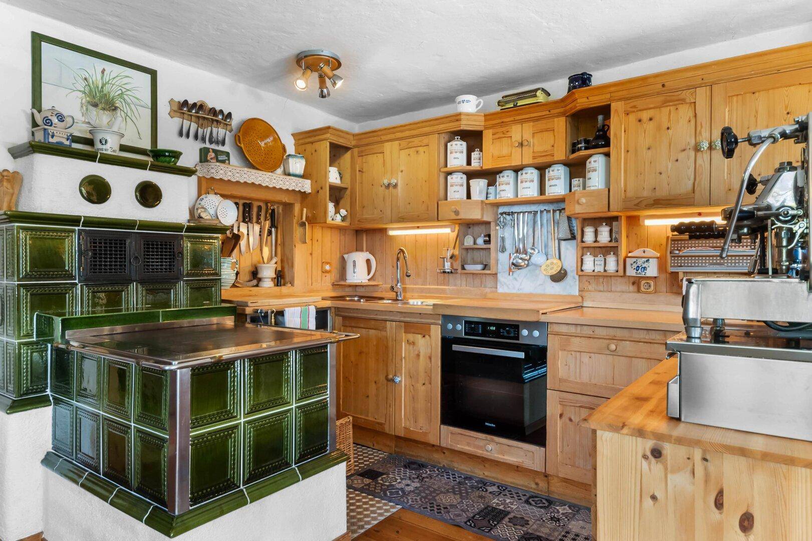 Traditionelle Holzküche mit rustikalen Schränken, Kachelofen und modernen Geräten.