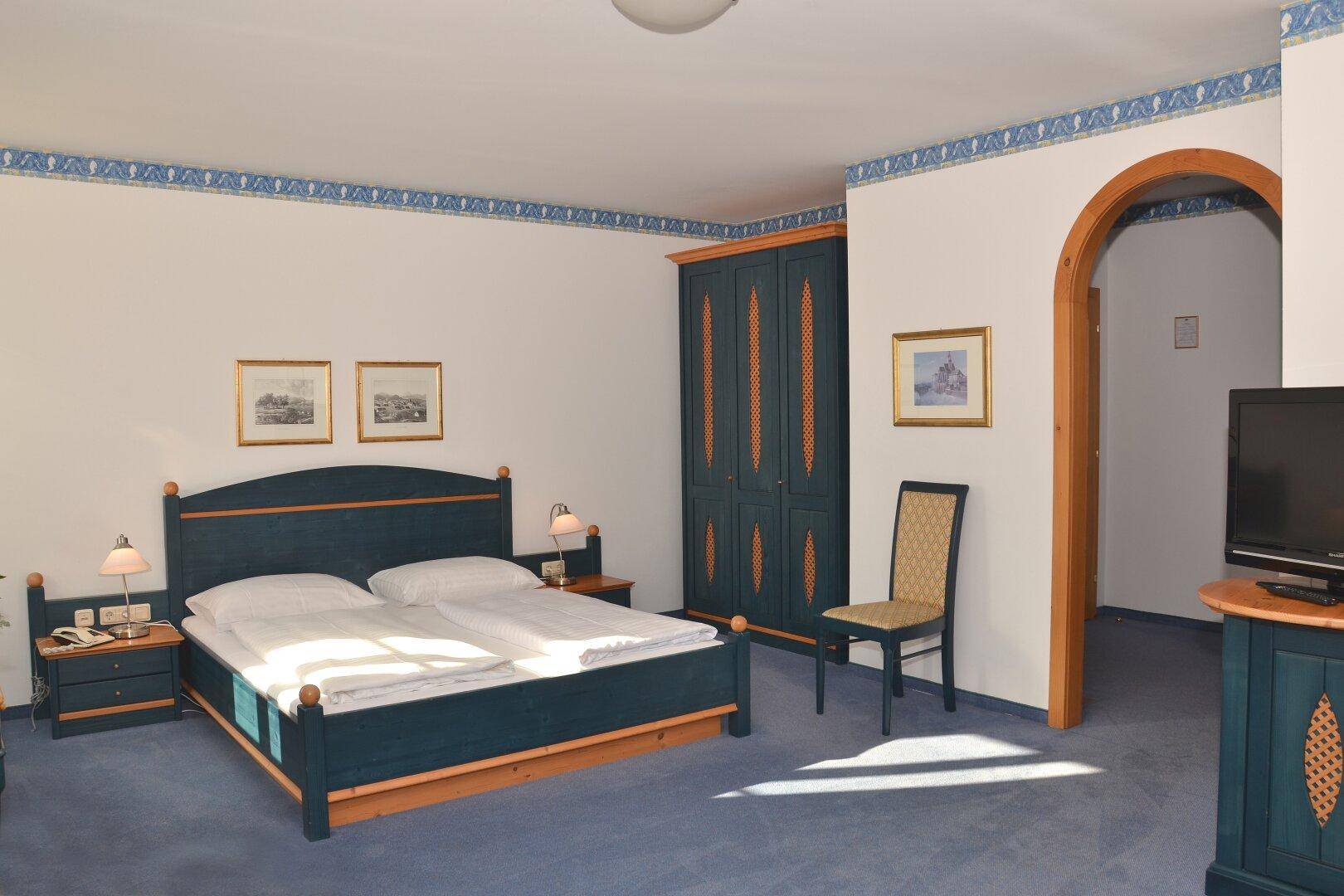 Gemütliches Schlafzimmer mit blauem Doppelbett, passendem Kleiderschrank und traditioneller Dekoration.