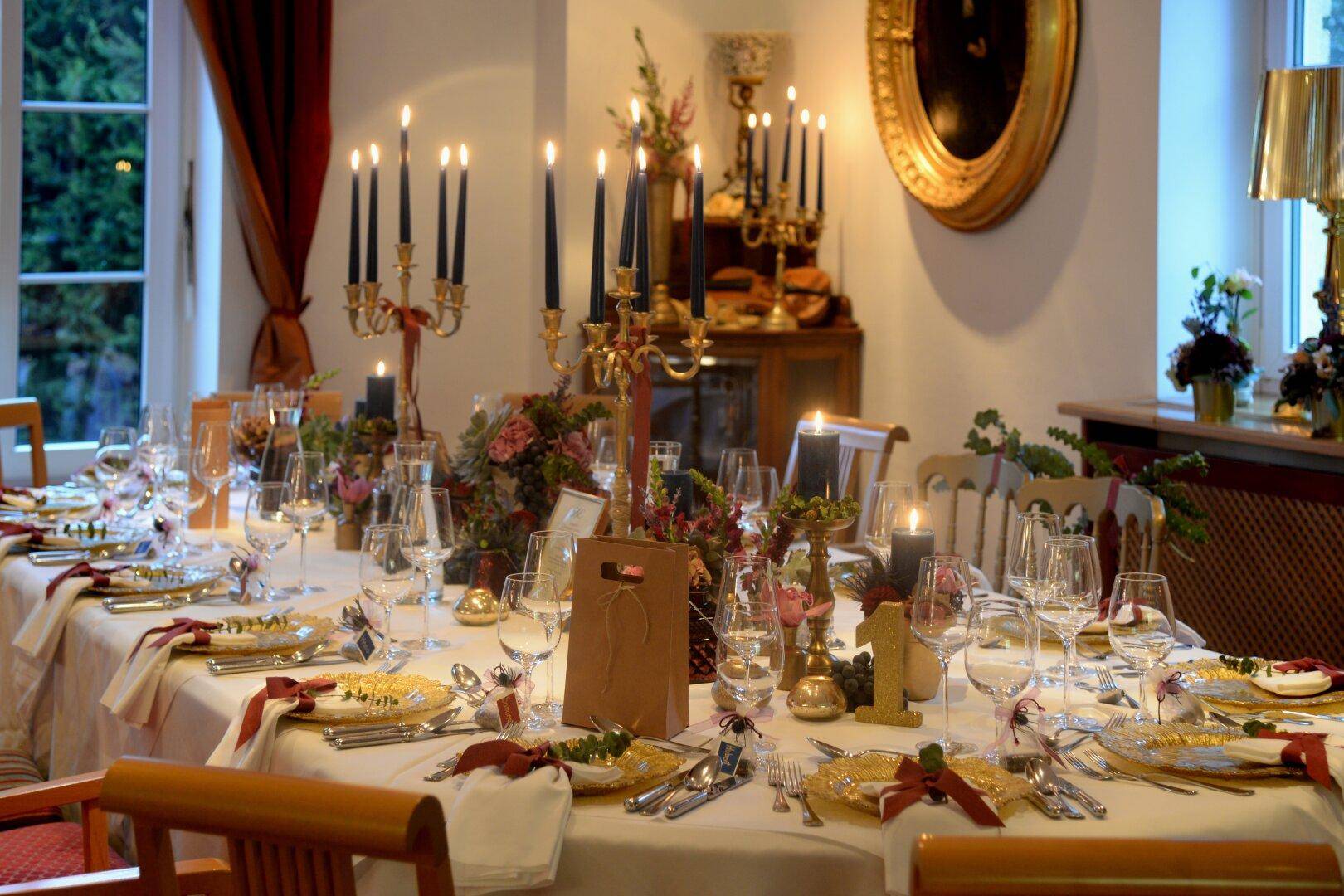 Festlich gedeckter Esstisch mit Kerzenleuchtern und Blumenarrangements in einem eleganten Speisesaal.
