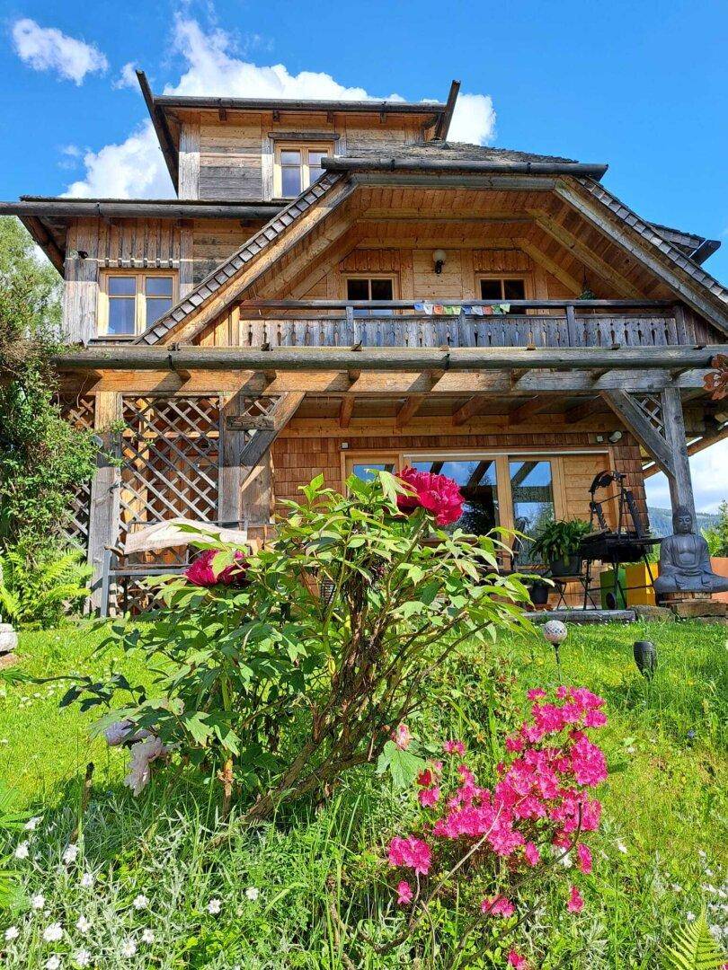 Charmantes Holzhaus mit blühenden Blumen im Vorgarten und traditioneller Architektur.