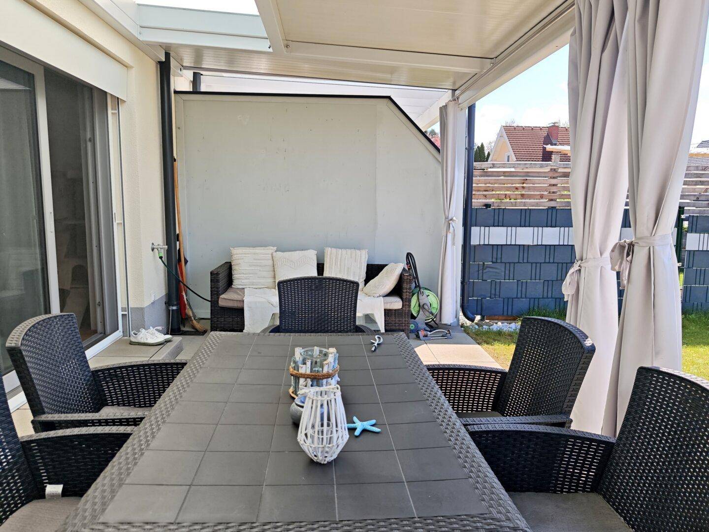 Überdachte Terrasse mit Esstisch und Lounge-Möbeln für entspannte Stunden im Freien.