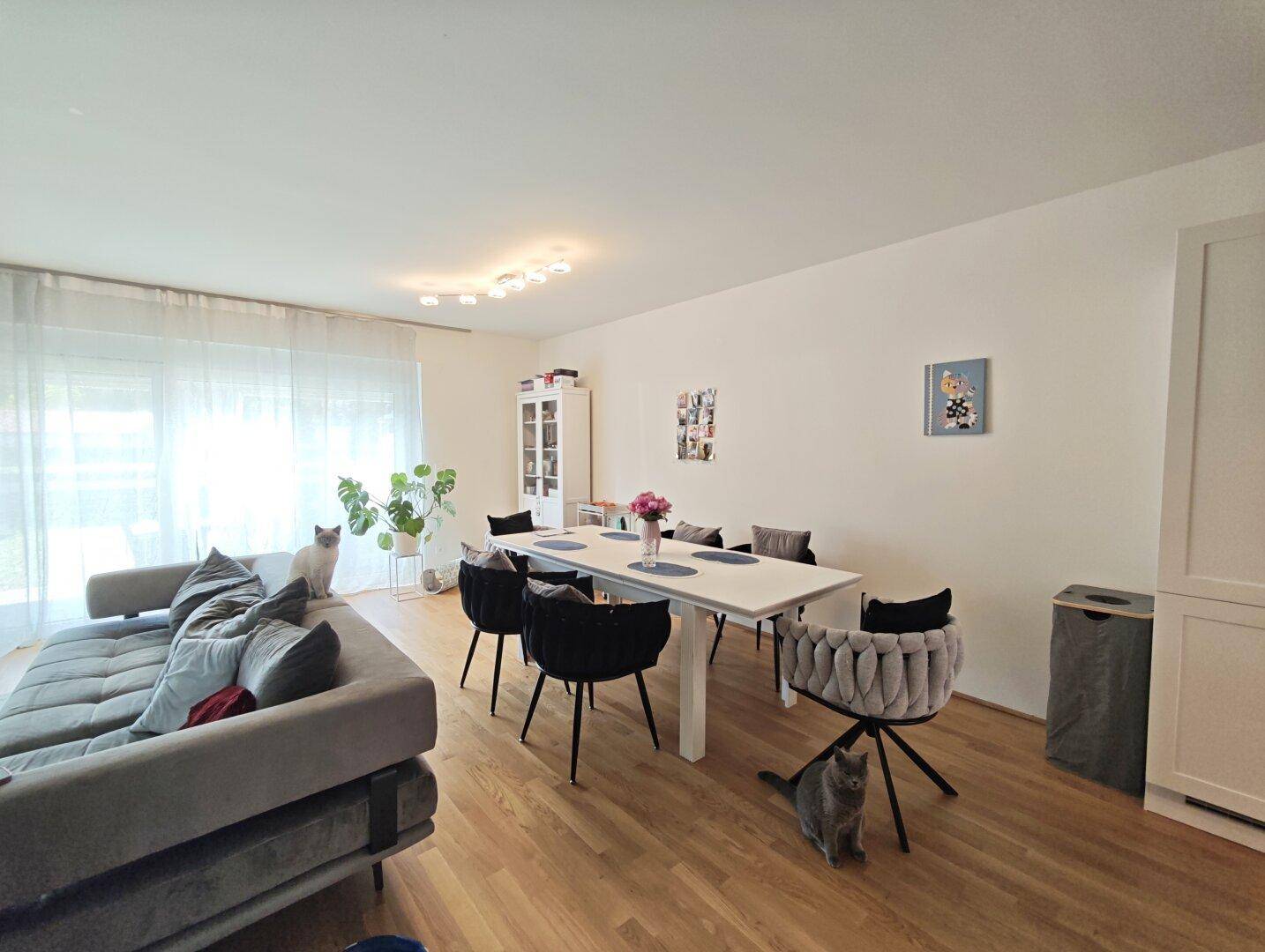 Heller Wohn-Essbereich mit bequemer Couch, Esstisch und Zugang zum Garten.