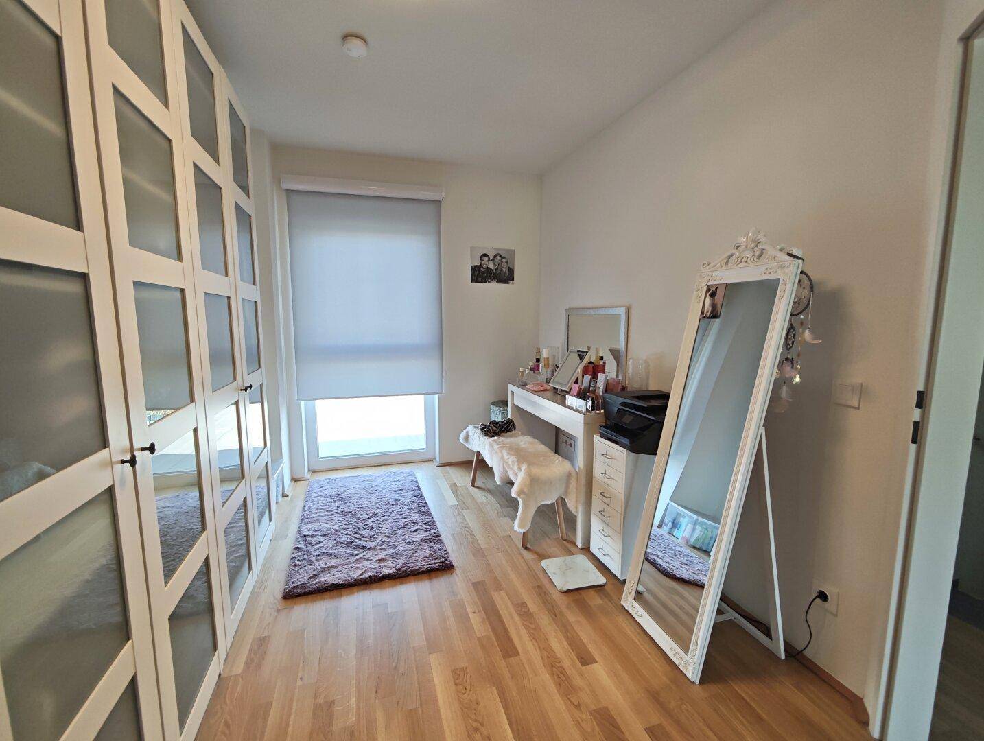 Ankleidezimmer mit Einbauschränken, Schminktisch und großem Spiegel.