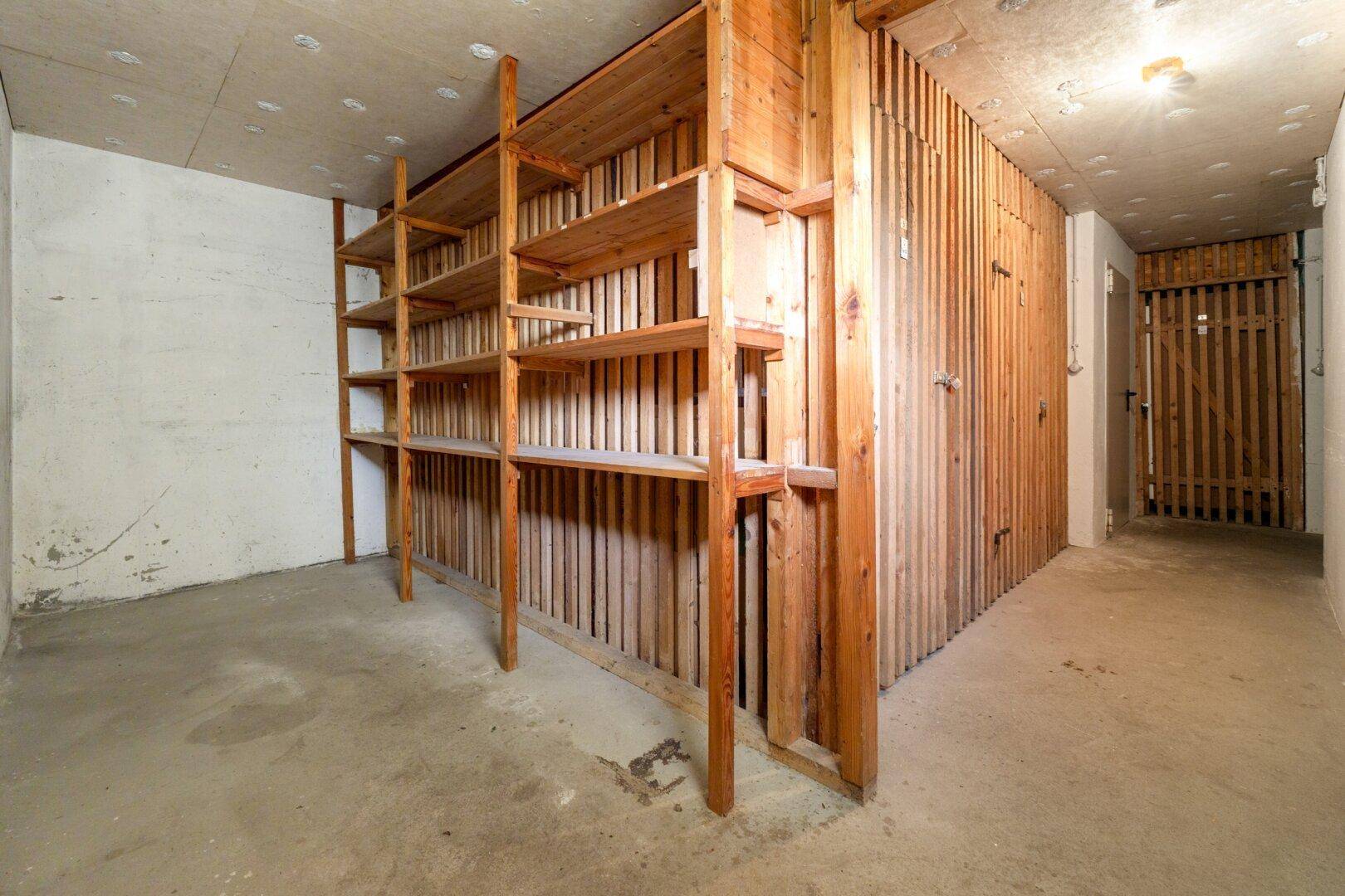 Geräumiger Kellerraum mit Holzregalen und Betonboden, ideal als Abstellraum nutzbar.