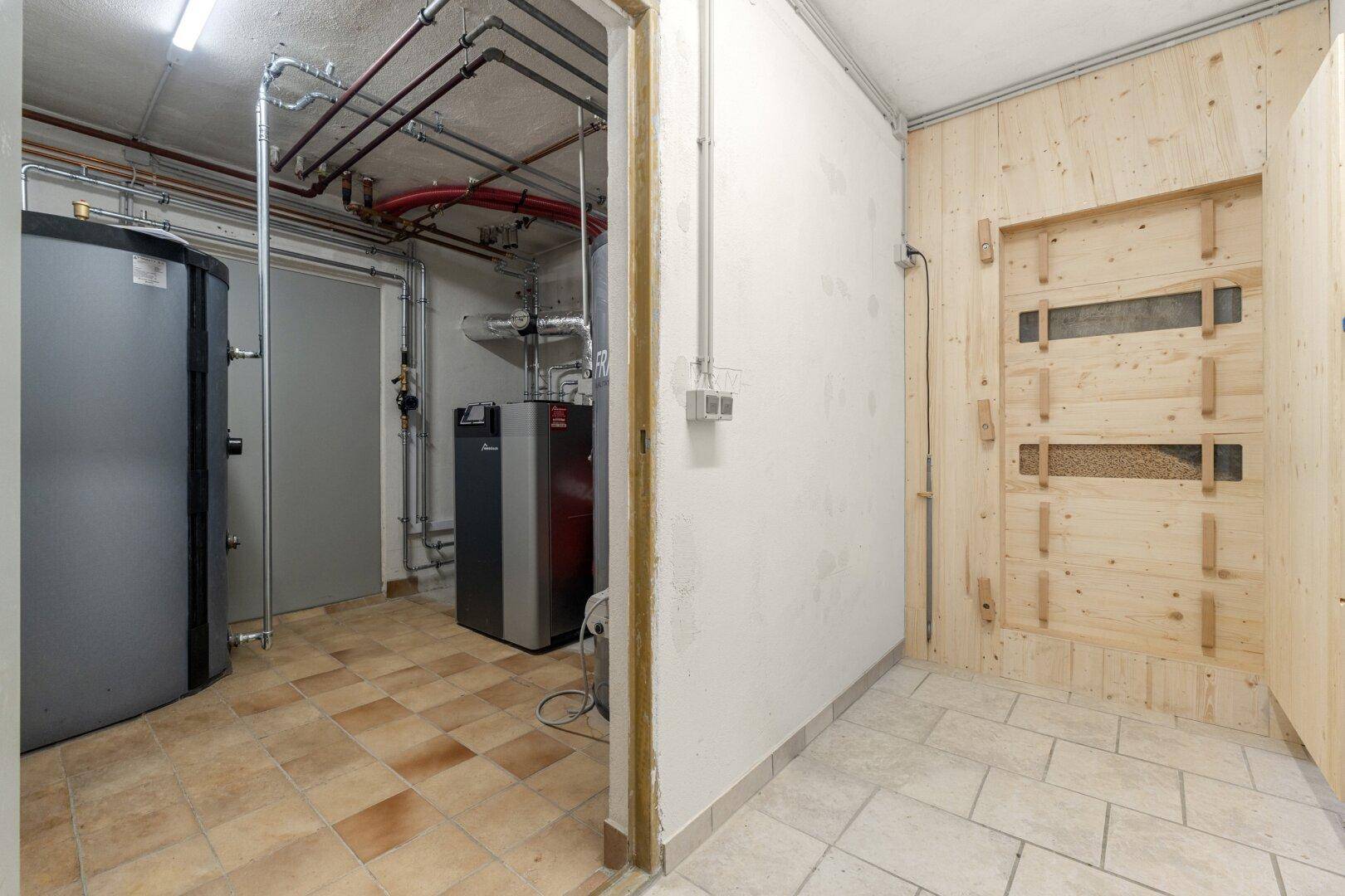 Technikraum mit Heizungsanlage und angrenzendem Lagerbereich für Brennmaterial.