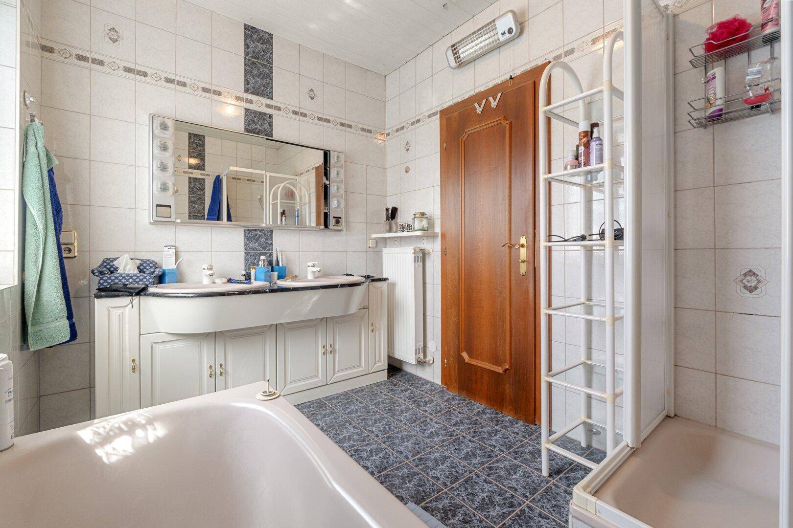 Badezimmer mit Badewanne, Dusche und traditionellen Fliesen in Weiß und Blau.