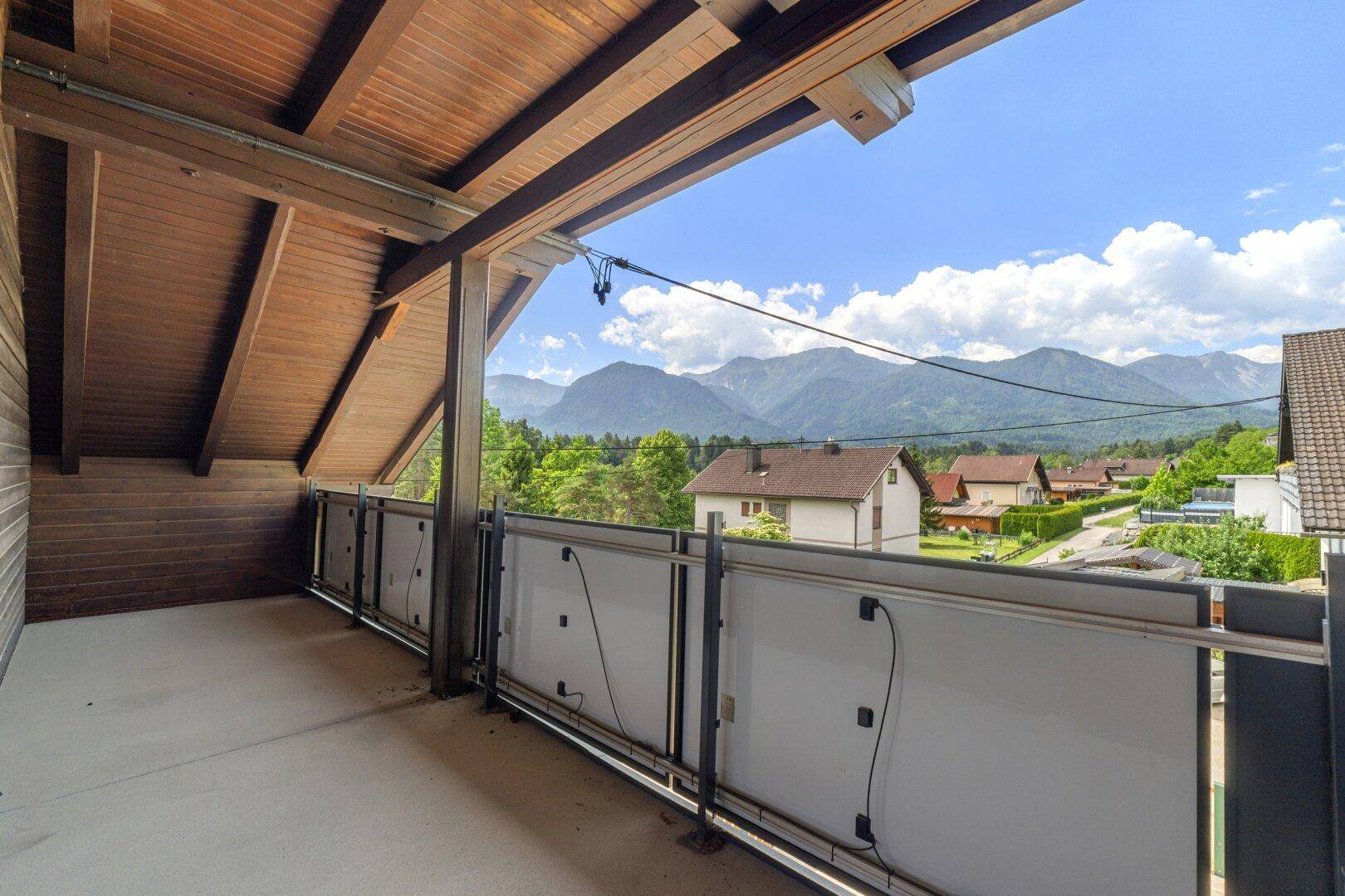 Überdachter Balkon mit Holzbalken und weitem Blick auf die umliegende Berglandschaft.