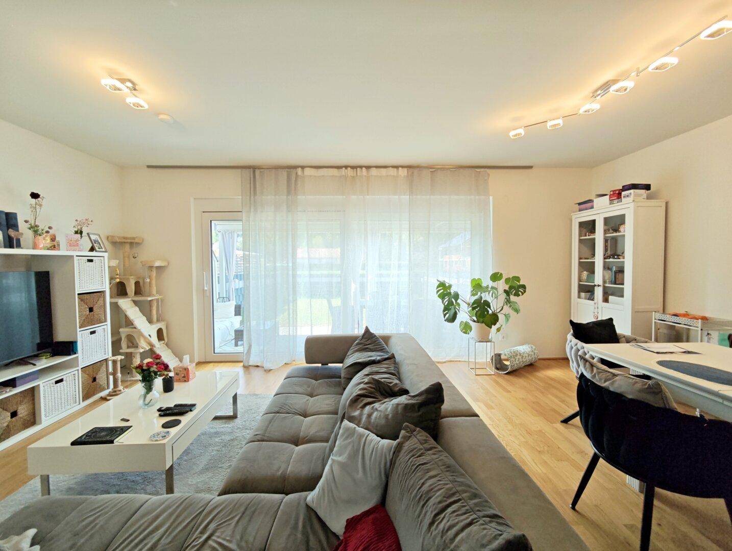 Geräumiger Wohnbereich mit großem Sofa, TV-Möbel und Blick ins Grüne.