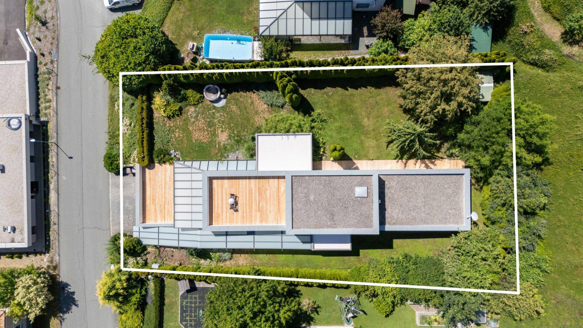 Luftaufnahme des Grundstücks mit modernem Haus, Garten, Pool und Terrassenflächen.