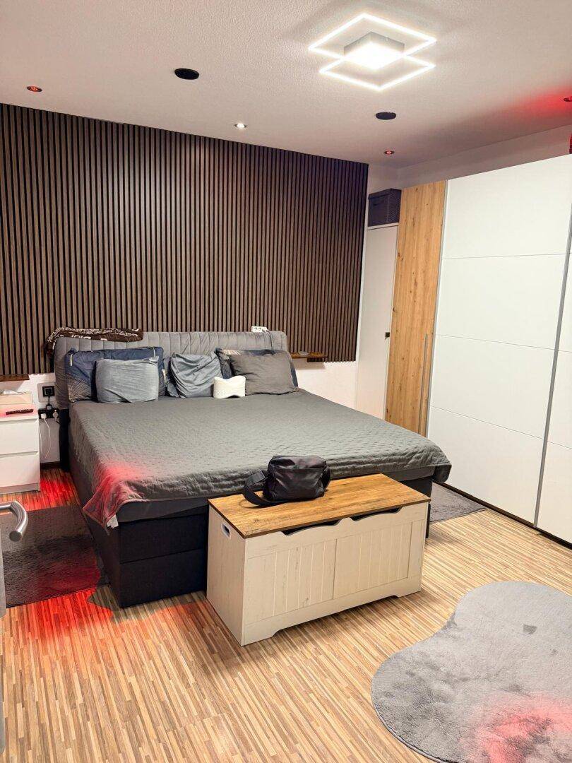 Modernes Schlafzimmer mit Holzwandverkleidung, großem Bett und integriertem Kleiderschrank.