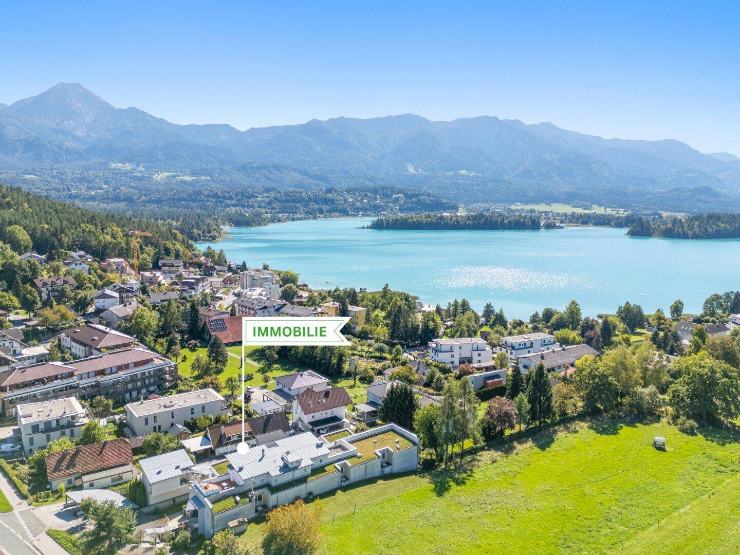 Panoramablick auf eine Siedlung am Seeufer mit majestätischer Bergkulisse im Hintergrund.