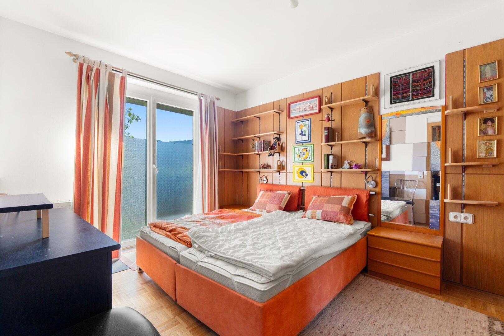 Gemütliches Schlafzimmer mit Doppelbett, Holzwandverkleidung und direktem Zugang zu einem Außenbereich.