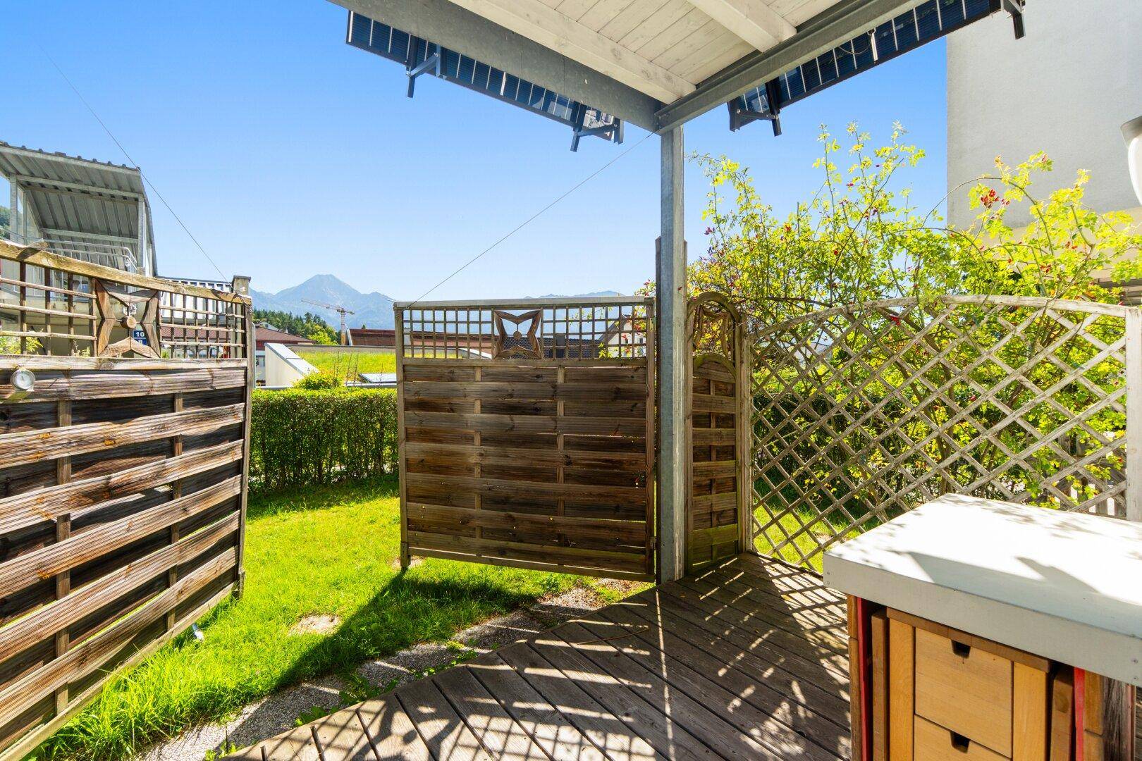Überdachte Terrasse mit Holzdeck, Sichtschutz und einem weiten Blick auf die umliegende Berglandschaft.
