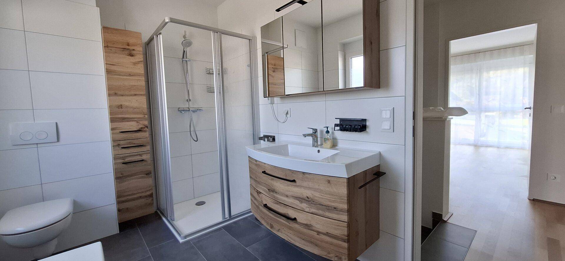 Modernes Badezimmer mit Duschkabine, Holzwaschtisch und weißen Fliesen.