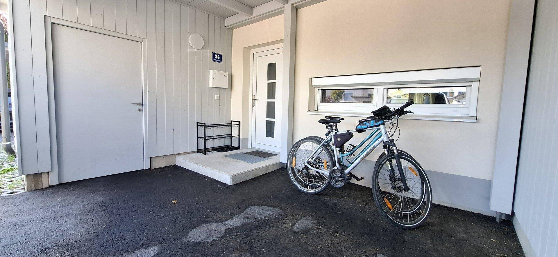 Eingangsbereich eines Reihenhauses mit überdachtem Carport und Abstellmöglichkeit für Fahrräder.