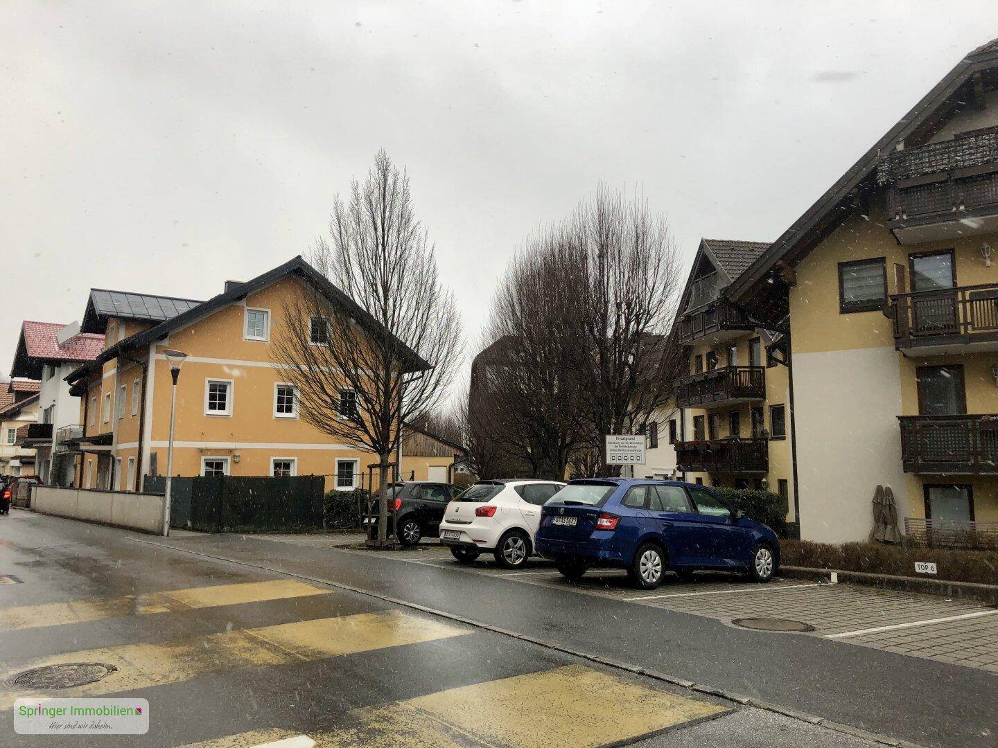 Außenansicht des Gebäudes mit angrenzenden Parkplätzen und weiteren Wohnhäusern in der Umgebung.