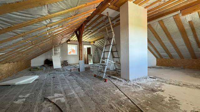 Dachboden im Rohzustand mit sichtbaren Holzbalken und viel Potenzial zum Ausbau.
