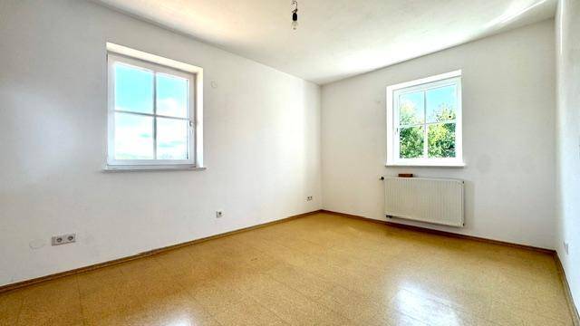 Zimmer mit hellem Boden, Fenster und Heizkörper, bereit zur individuellen Gestaltung.