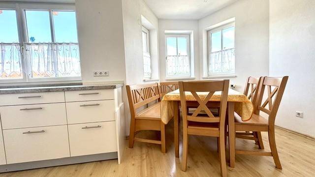Gemütlicher Essbereich in der Küche mit Holztisch, Eckbank und Blick ins Grüne.