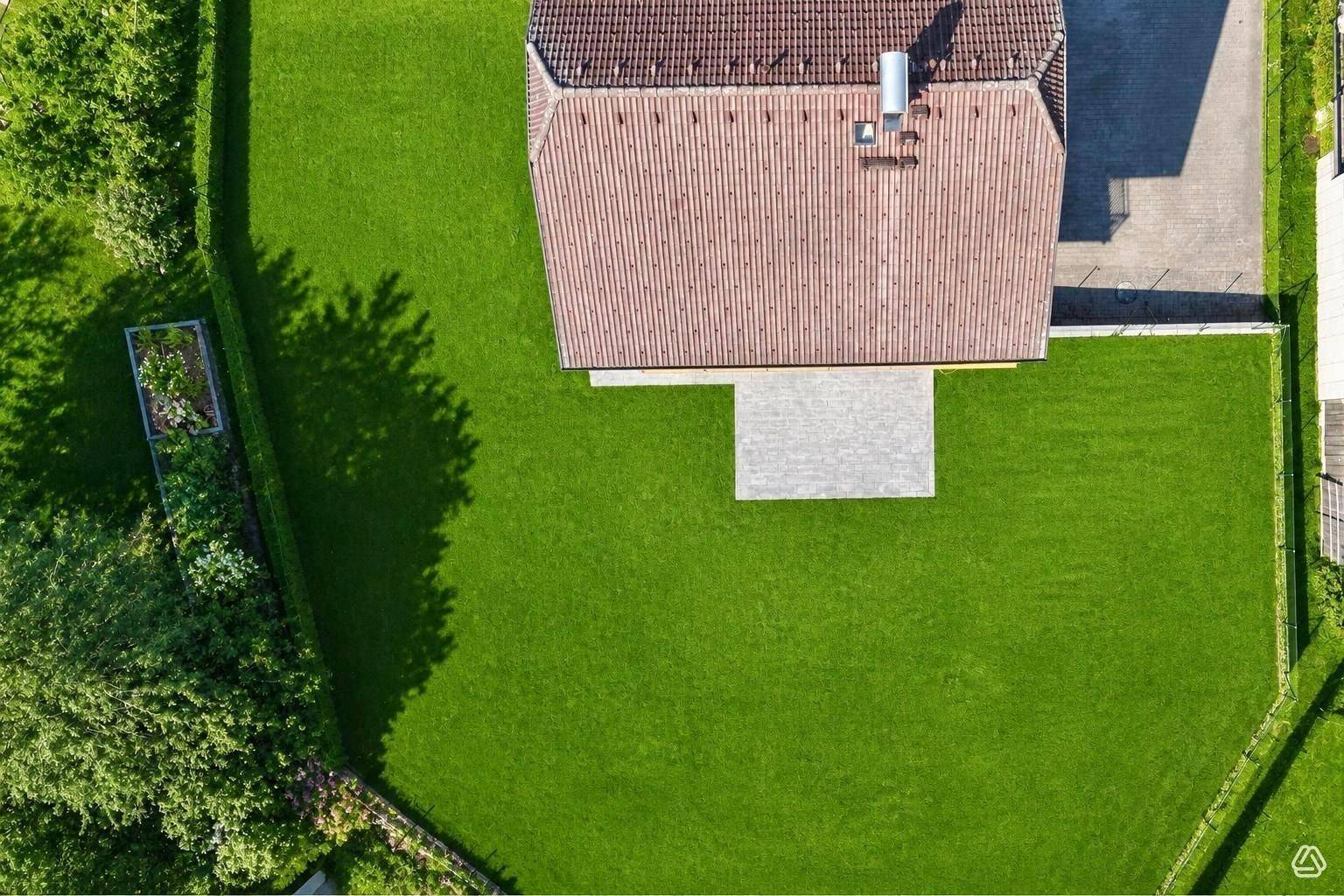 Luftaufnahme des Hauses mit großem, gepflegtem Rasen und angrenzendem Gartenbereich.