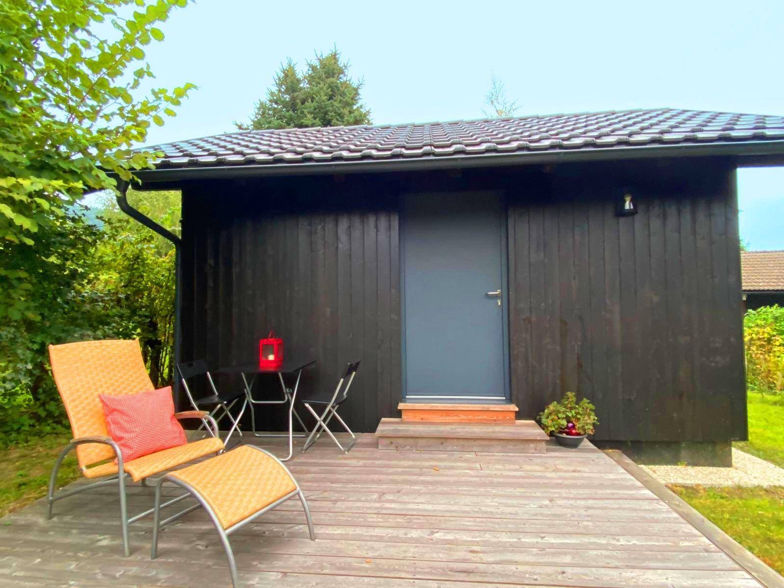 Holzterrasse vor dem kleinen Haus mit bequemen Liegestühlen und Blick ins Grüne.