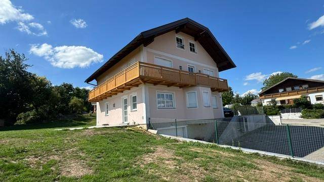 Seitenansicht des Hauses mit Balkon, Garten und Zufahrt zur Tiefgarage.