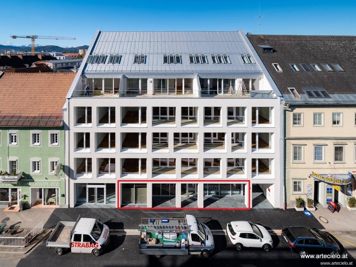 Luftaufnahme eines modernen Neubaus mit Mansarddach und großen Fensterfronten im Erdgeschoss.