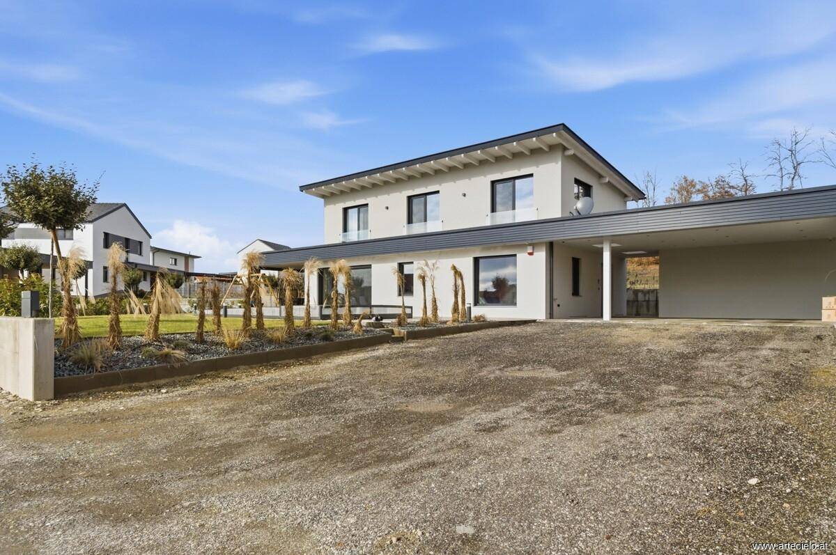 Ansicht des modernen Einfamilienhauses von der Einfahrt mit Carport und gepflegter Außenanlage.